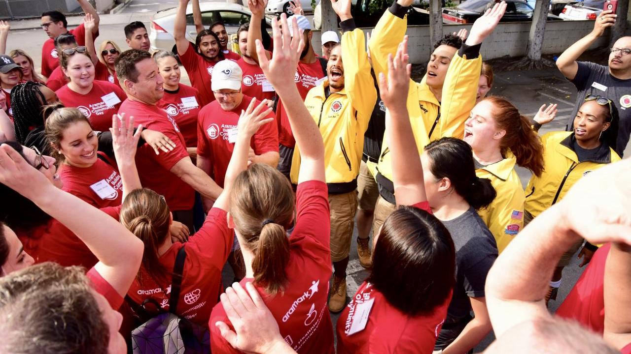 Volunteers raise their hands as a part of an outdoor “huddle”