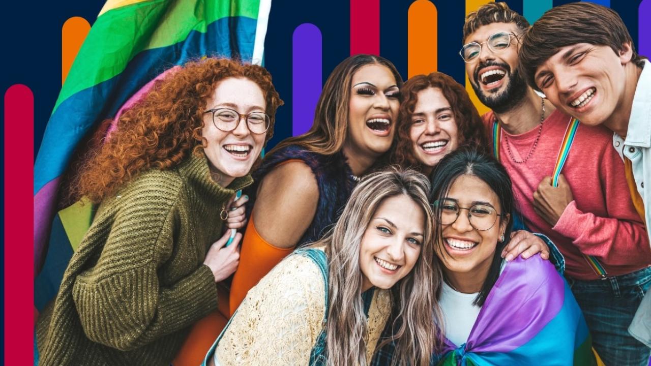 Group of seven people with a Pride flag in the background.