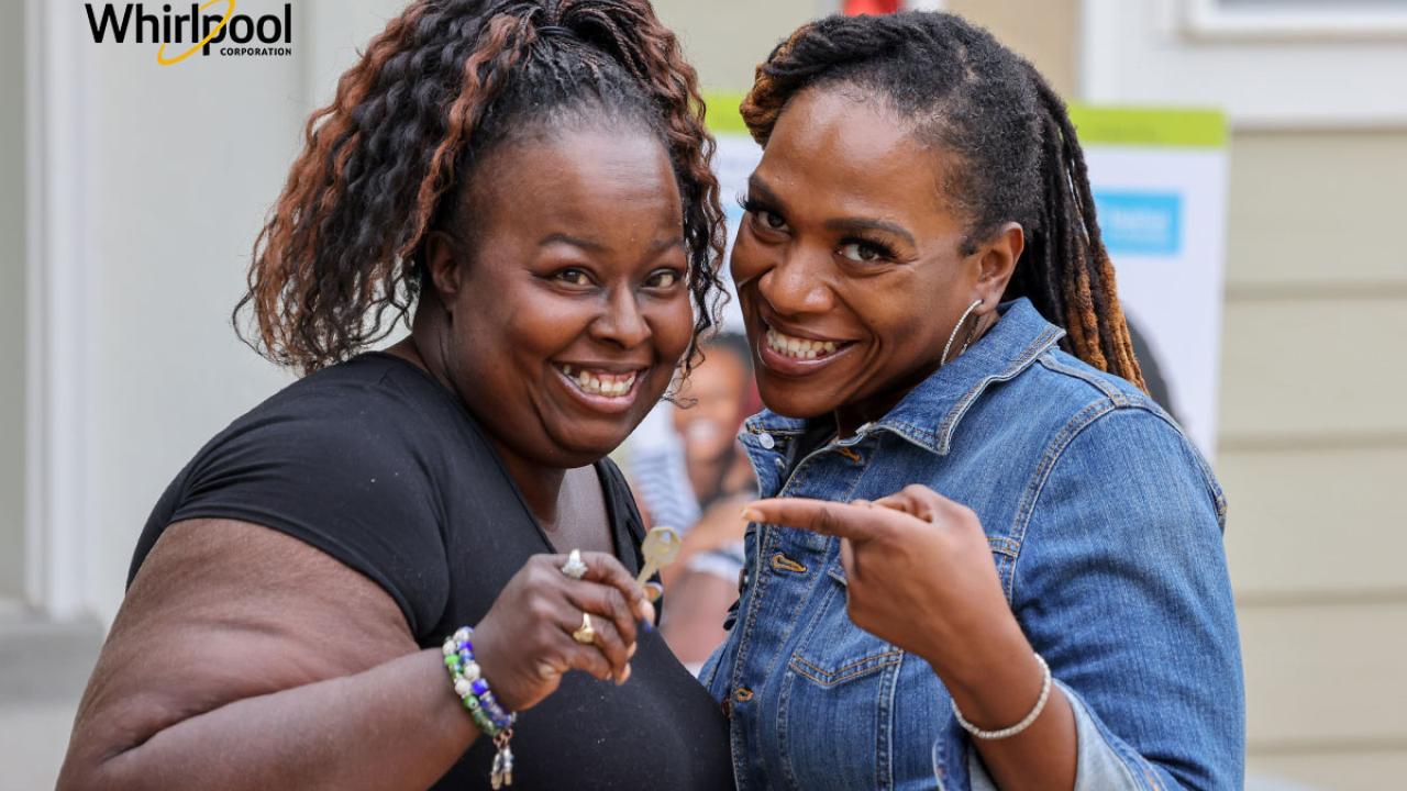 A woman in a denim jacket pointing to Latonya holding a house key