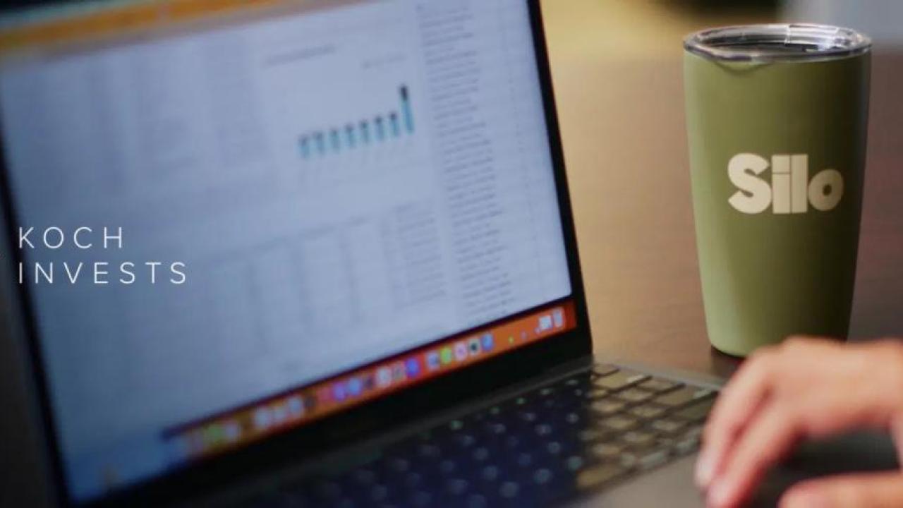Close up of a person using a laptop, with a Silo travel mug placed to the right-hand side of the laptop
