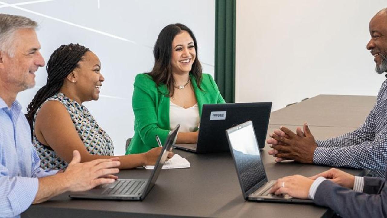 Lesly Luque and team at a conference table, some with open laptops.