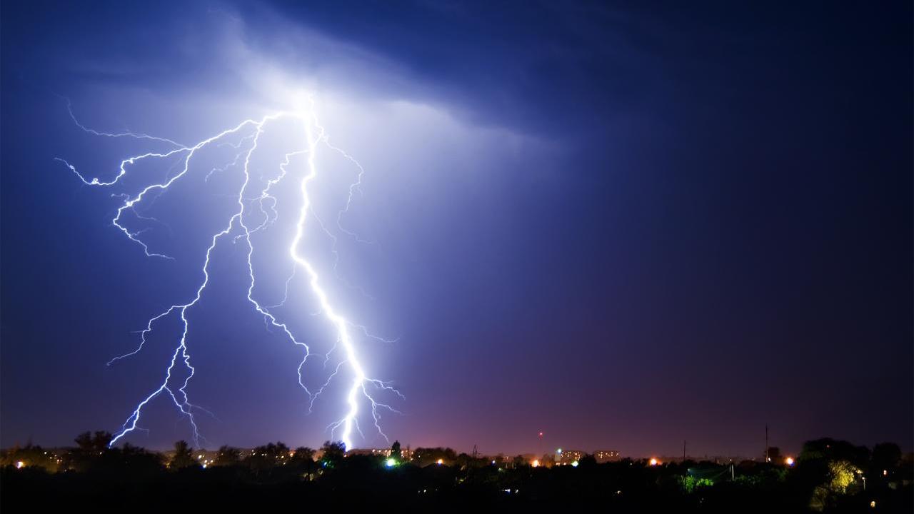 Nighttime lightning bolt above a cityscape 