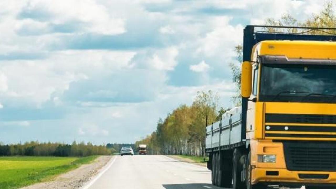 Yellow lorry driving down a road