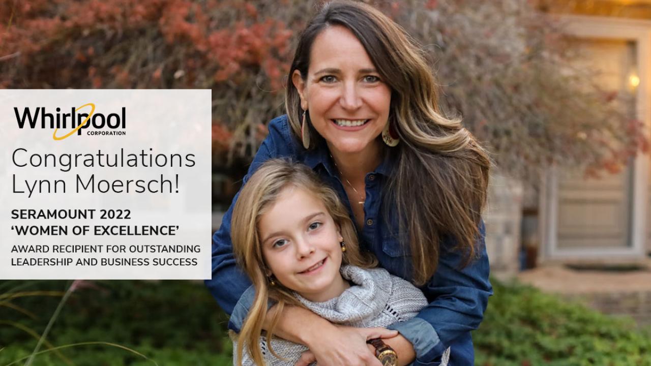 Lynn Moersch hugs a child outside a building with landscaping. "whirlpool- congratulations Lynn Moresch!" on the left.