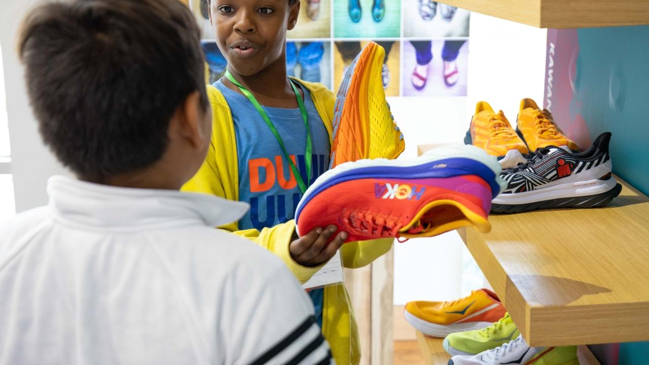 children holding Hoka shoes