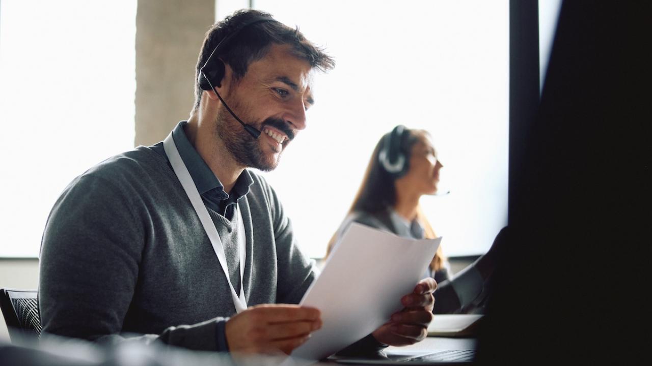 Two people shown wearing headsets in front of monitors.
