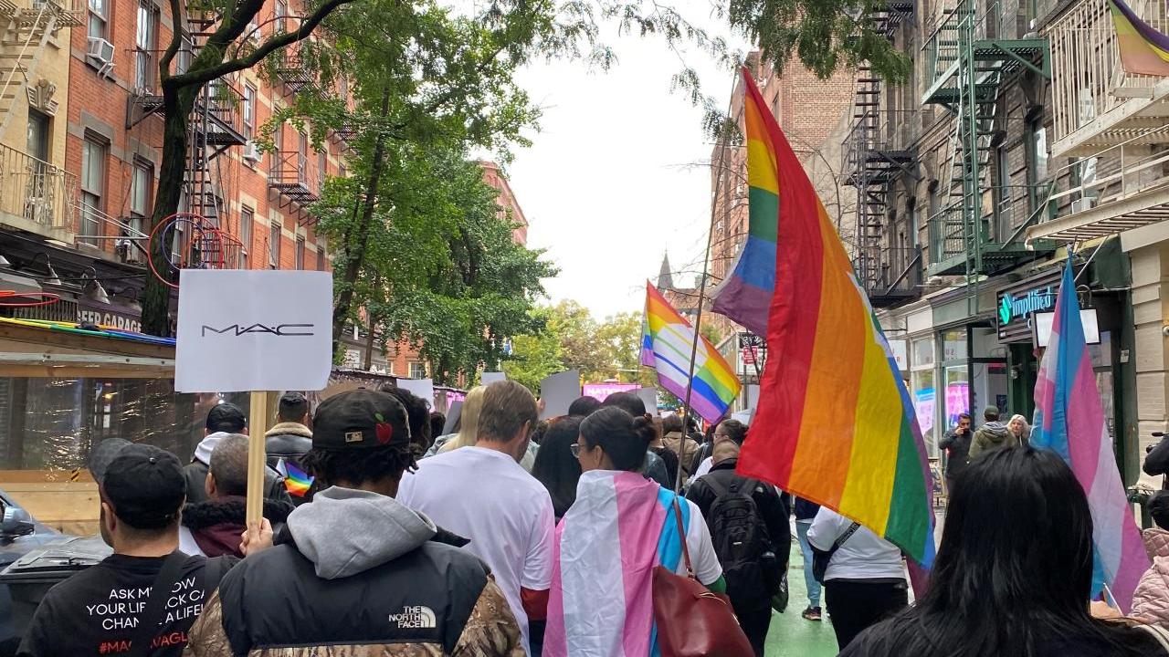 People marching down the street with signs and flags.