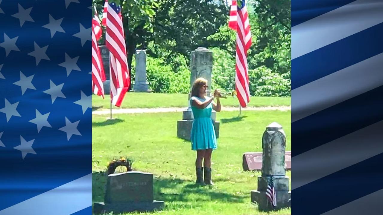 Marianne Masters playing a trumpet in a cemetary.