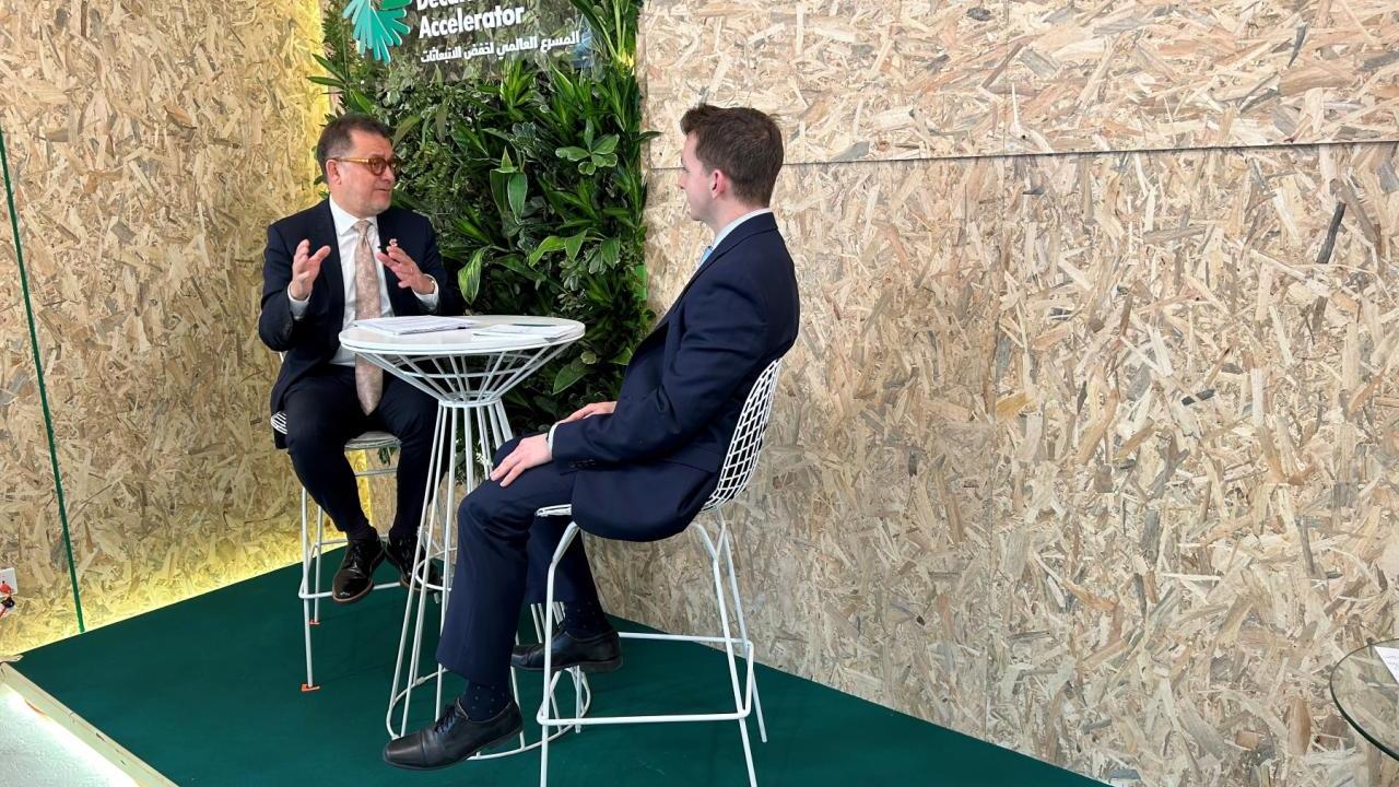 Two seated people talking.