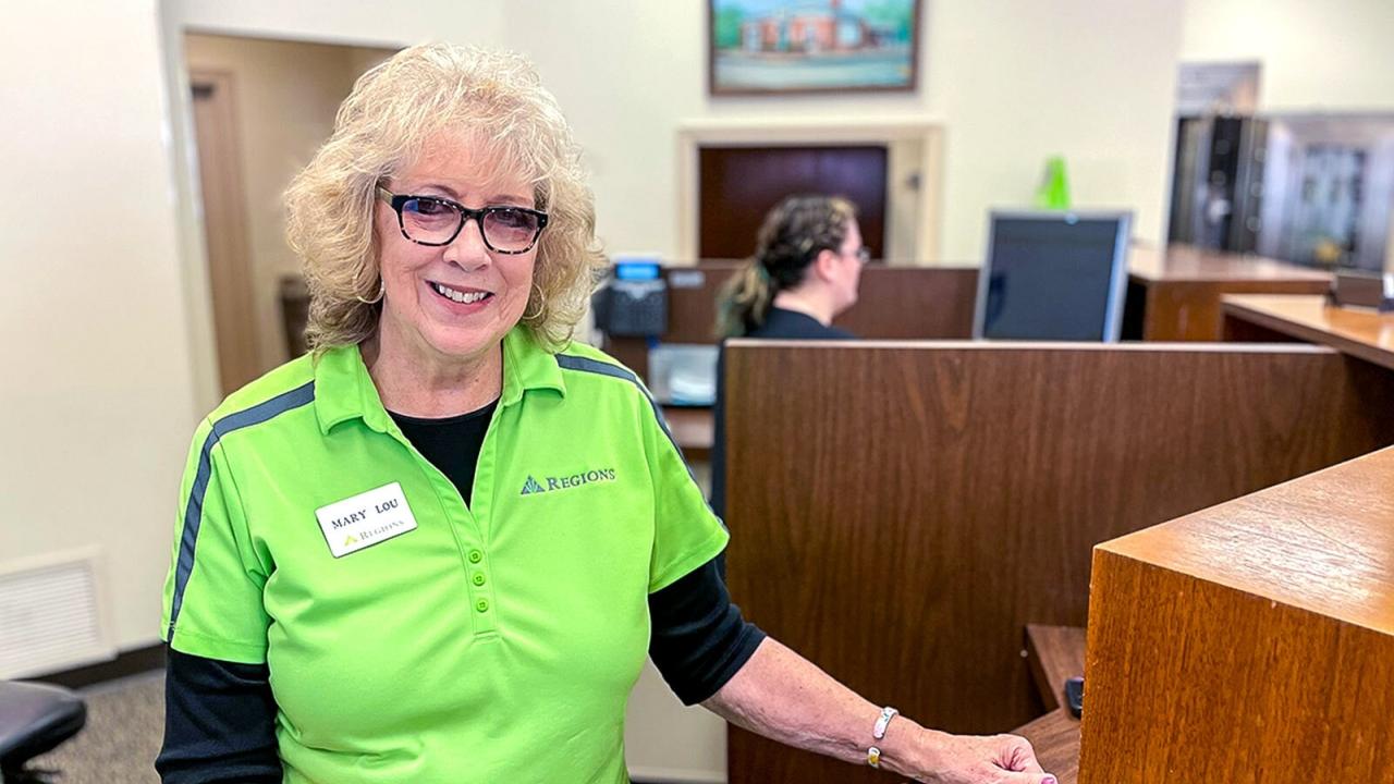 Mary Lou Schlueter in a green shirt at a teller's station