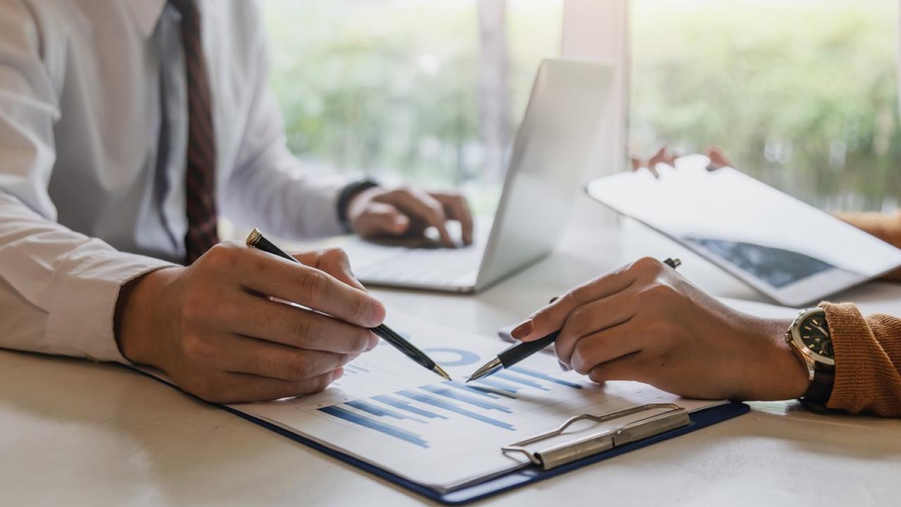two hands with pens pointing at a report