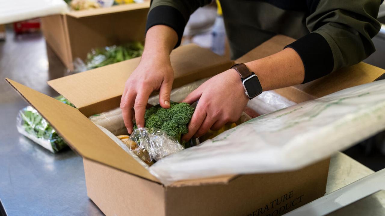 person packs vegetables into a box