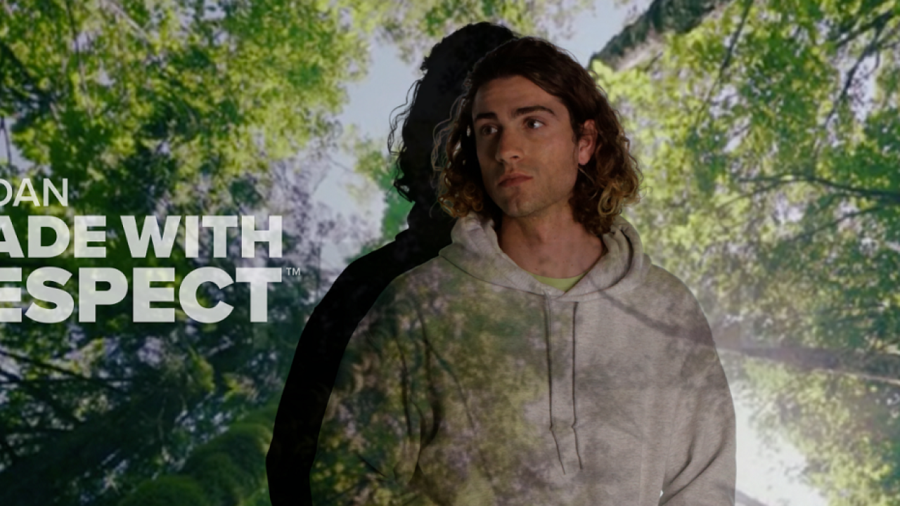 Person stands with forest background. reads: "Gildan, made with respect."