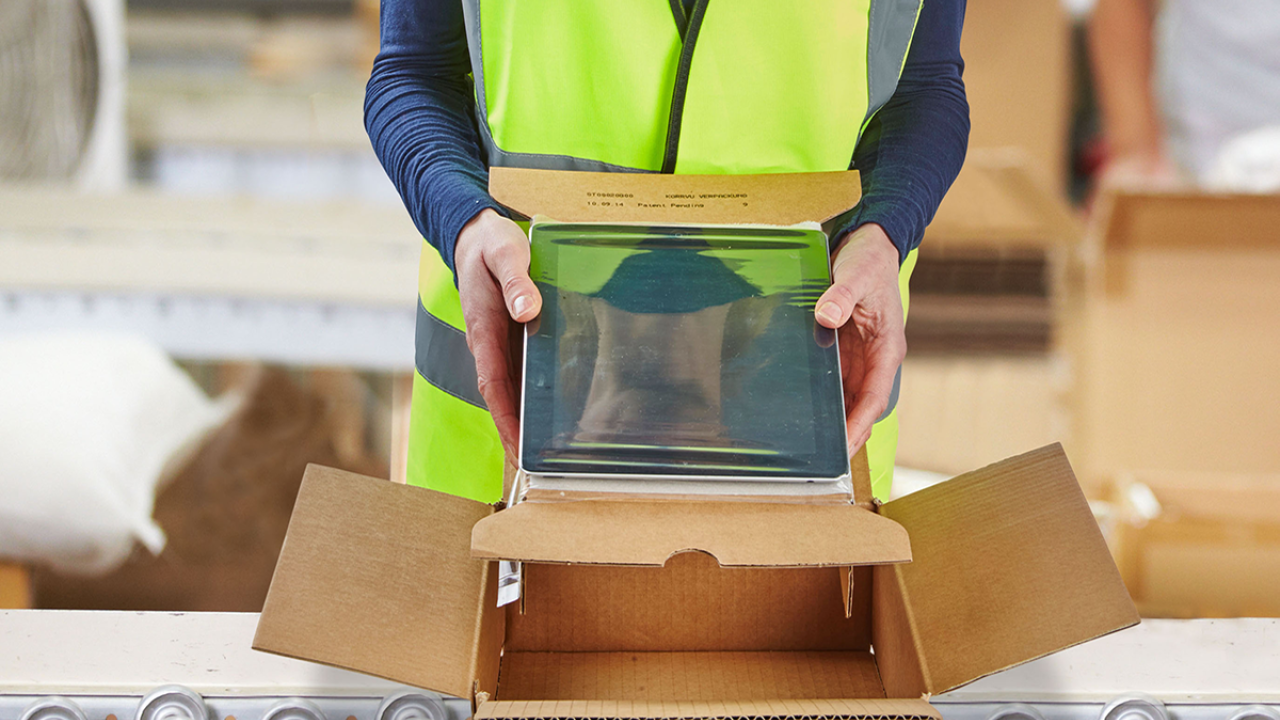 Item in a box held by a person in yellow vest