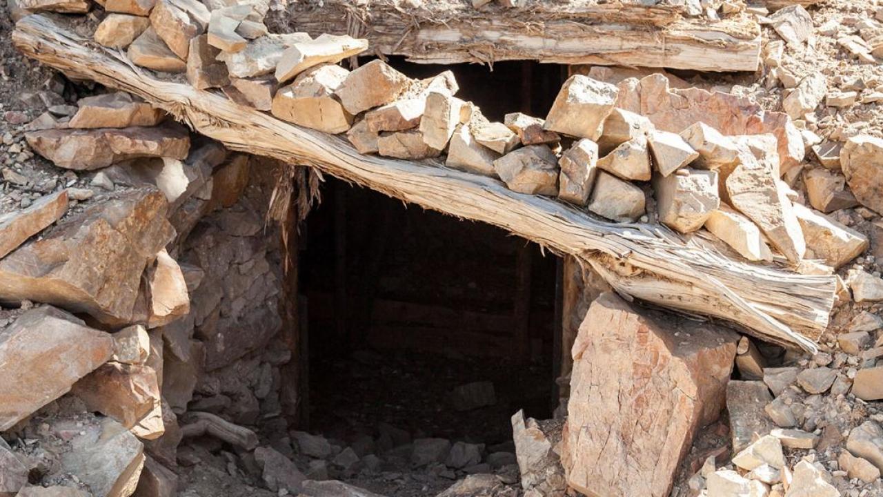 Opening to a mineshaft, rocks and wood create a doorway.