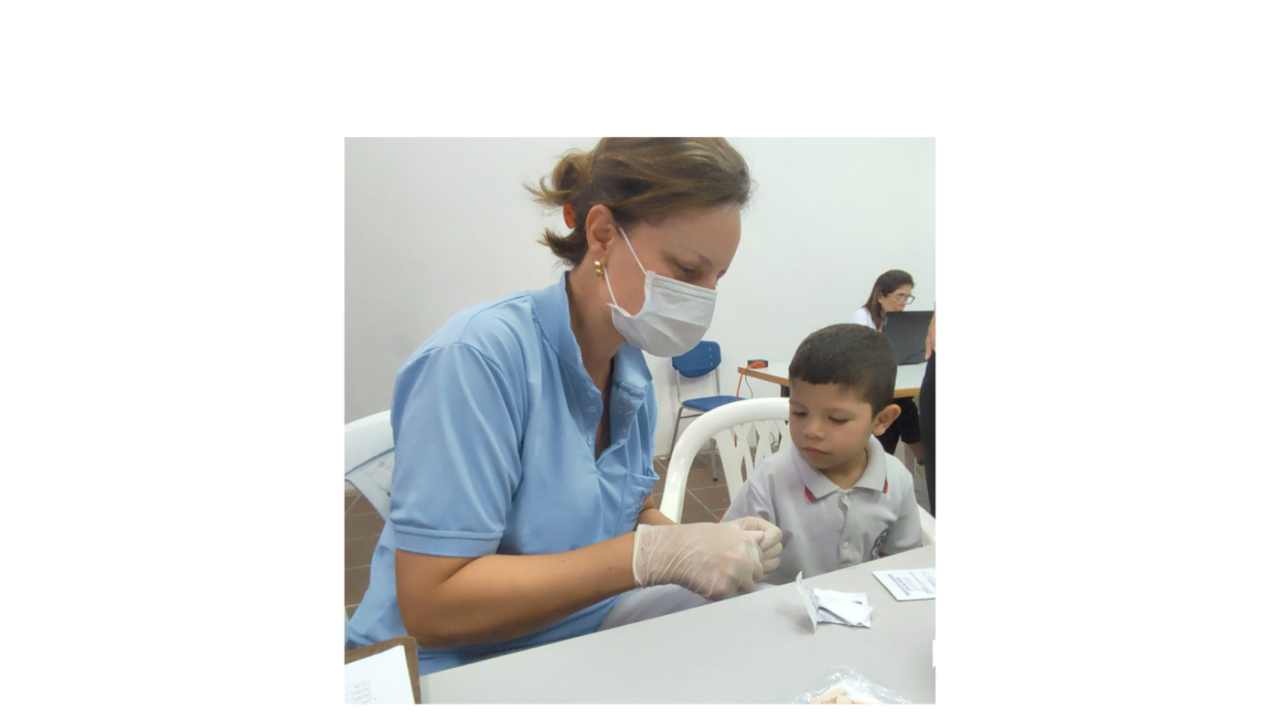 An adult in medical uniform giving a child a cup.
