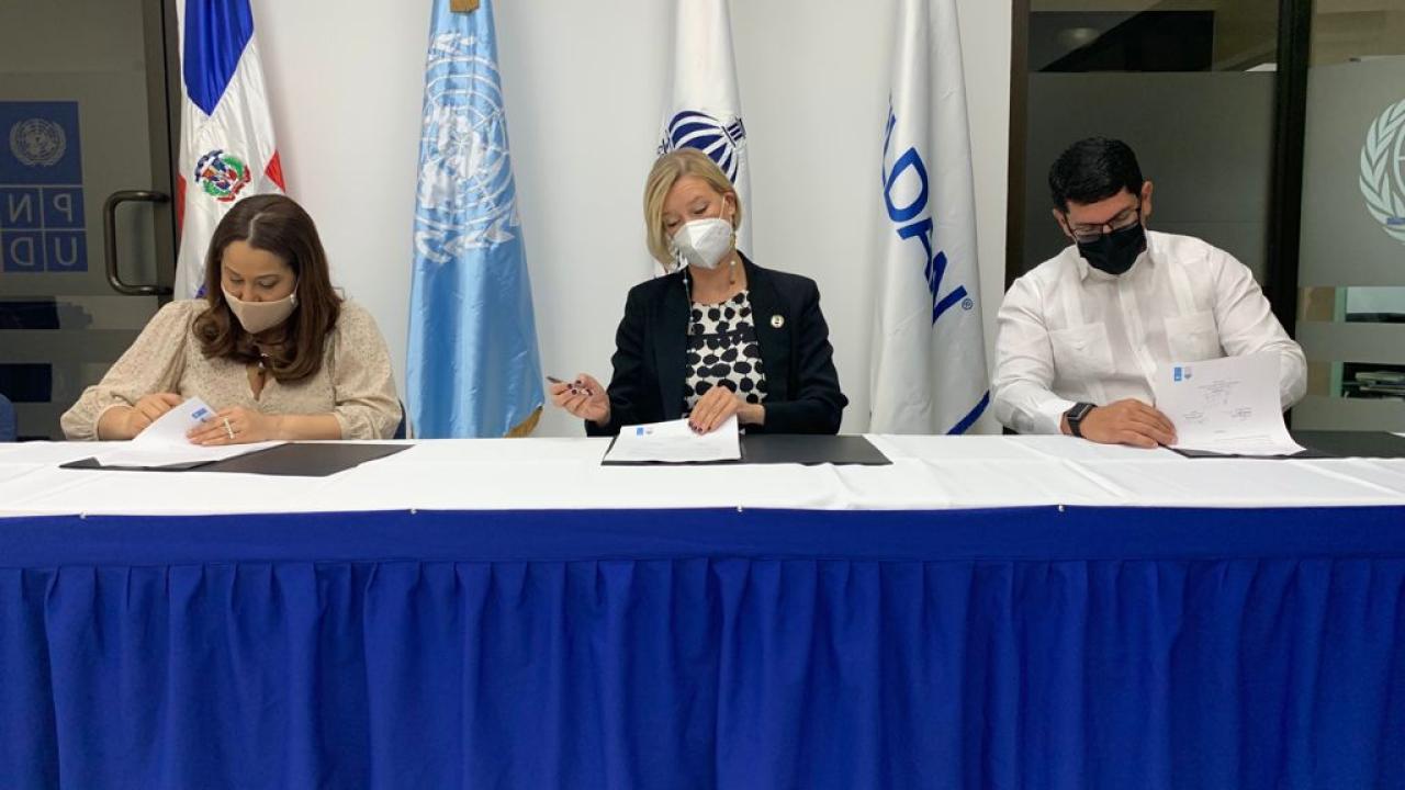 three people signing papers at table
