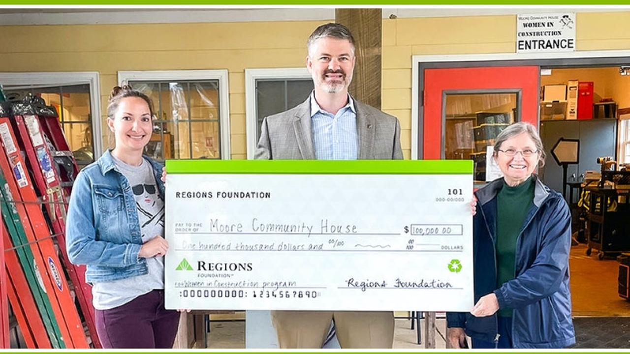 Three people holding check for $100,000 from Regions Foundation to Moore Community House