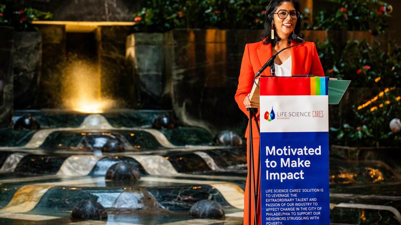 speaker at a lectern with a sign "Motivated to make impact"