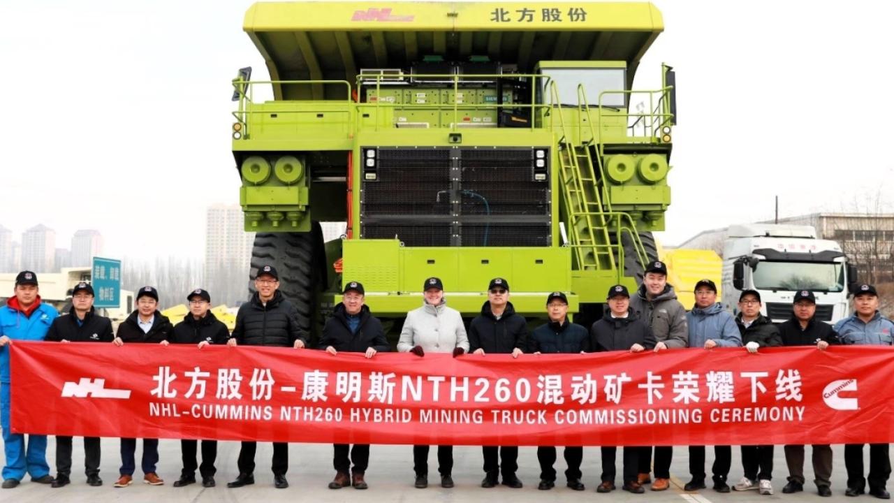 A line of people holding a line banner in front of a mining truck