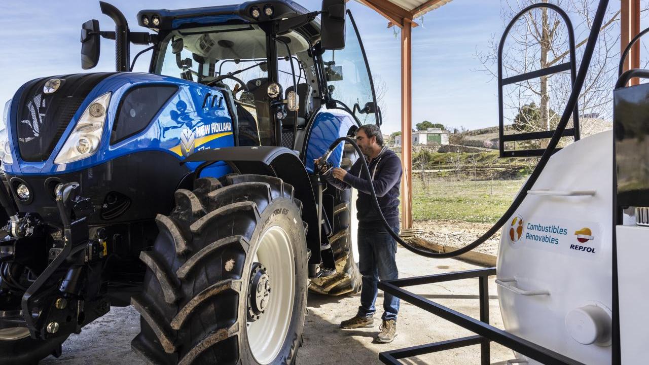 A person refueling a New Holland tractor