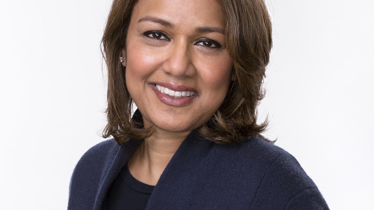Brown haired lady smiling with a navy blue jacket.