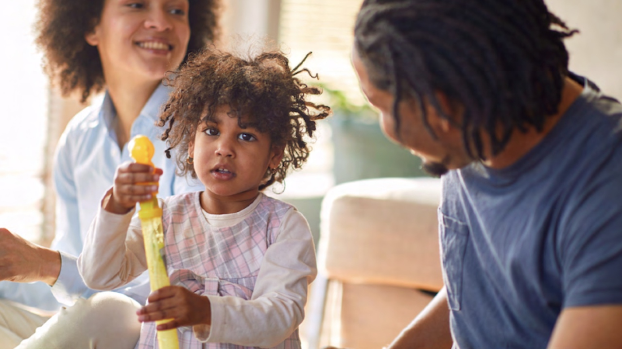 A family seated with their daughter holding a toy.