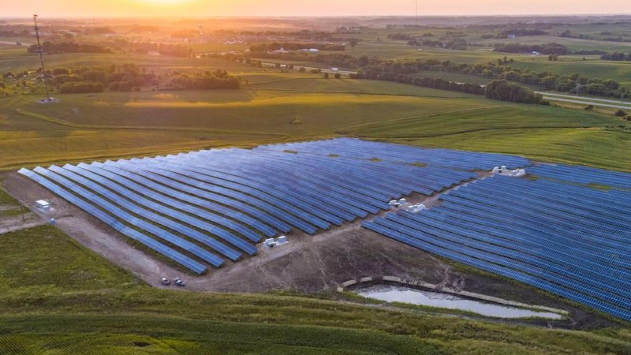 Solar panel array shown overhead with sun setting in the distance.