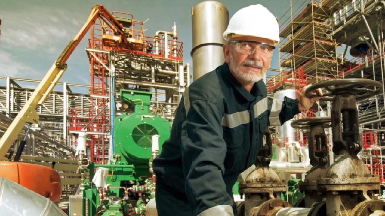 a worker in an industrial setting, cranes and scaffolding in the background
