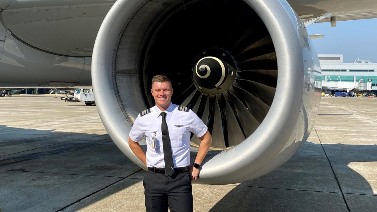 Pilot David Pettet standing in uniform in front of a plane engine