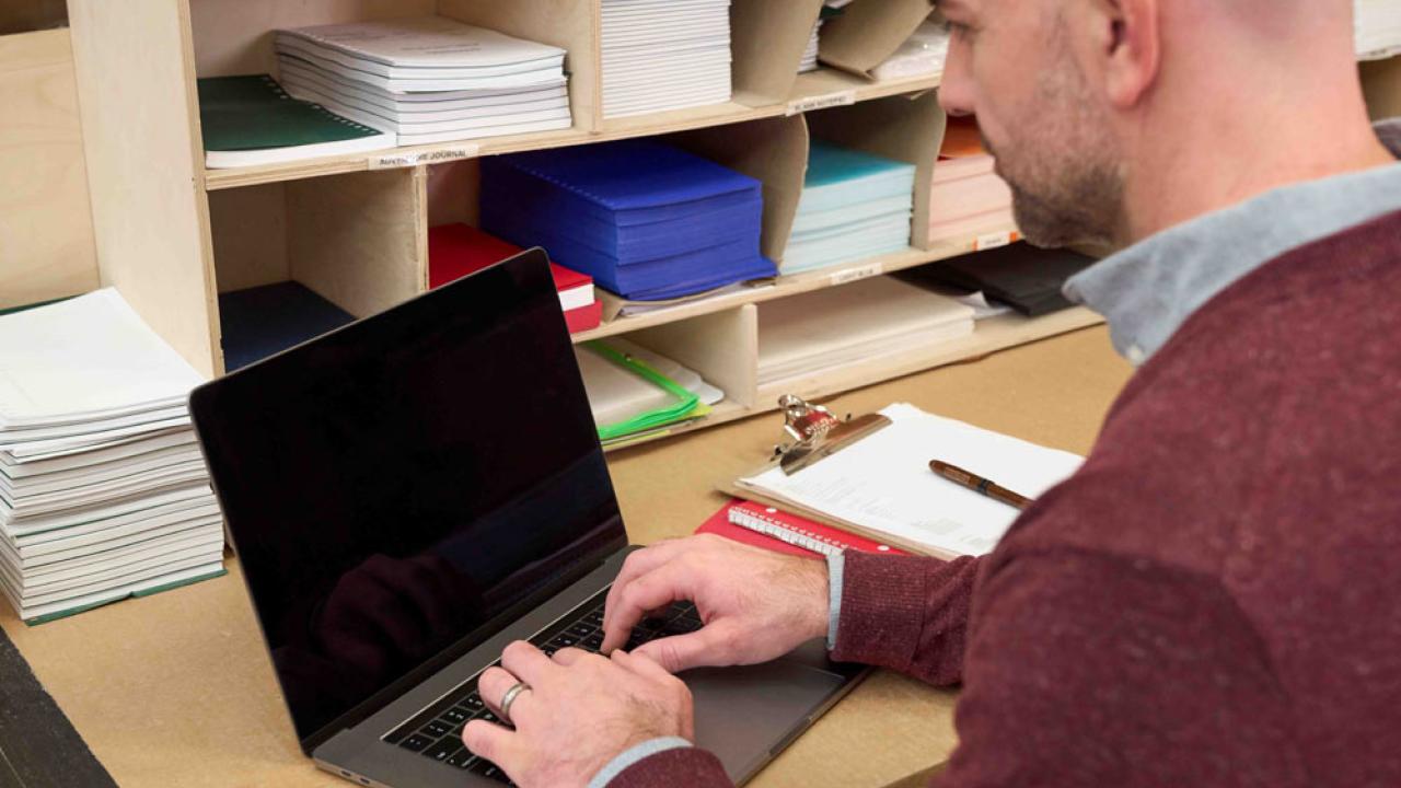 A person seated and in front of a laptop.