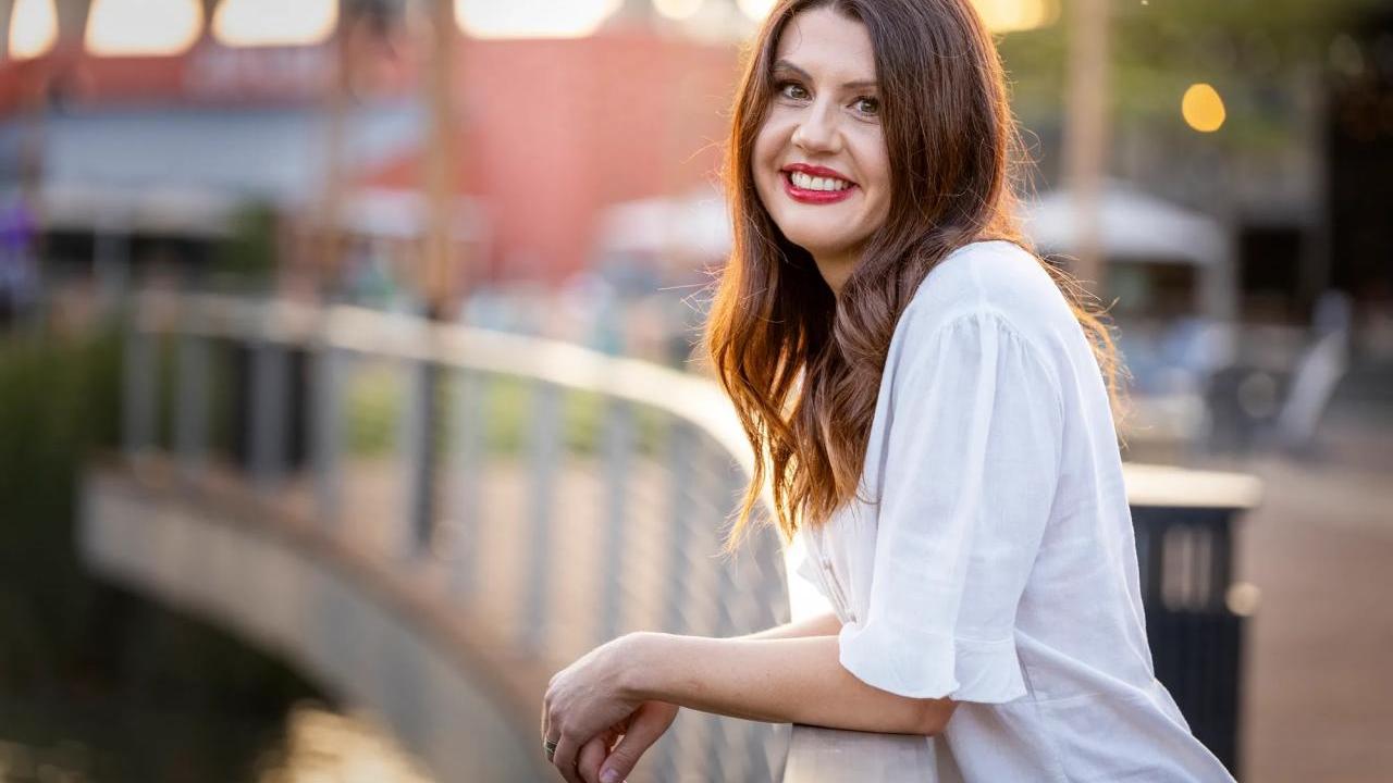 Nikki Jolly stood resting their arms on a bridge railing
