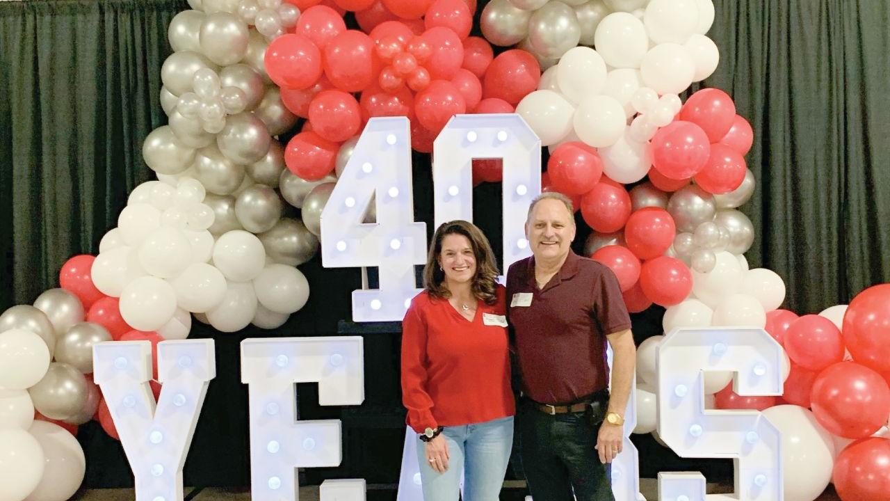 Two people standing in front of balloon display and sign reading "40 Years"