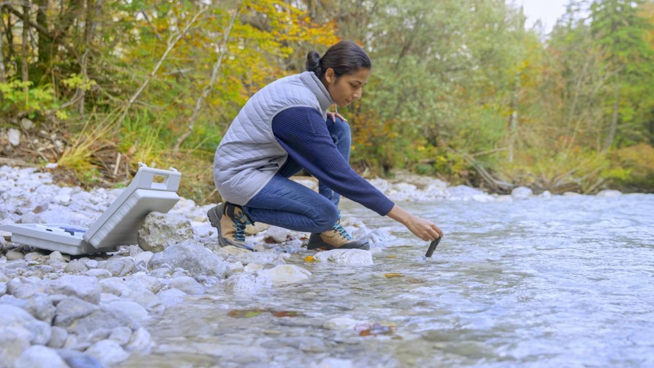 person collecting a water sample outside