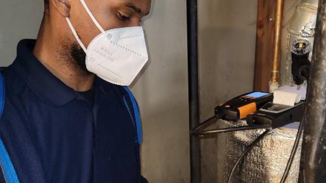 PSEG trainee, masked, is reading a gas meter during training.