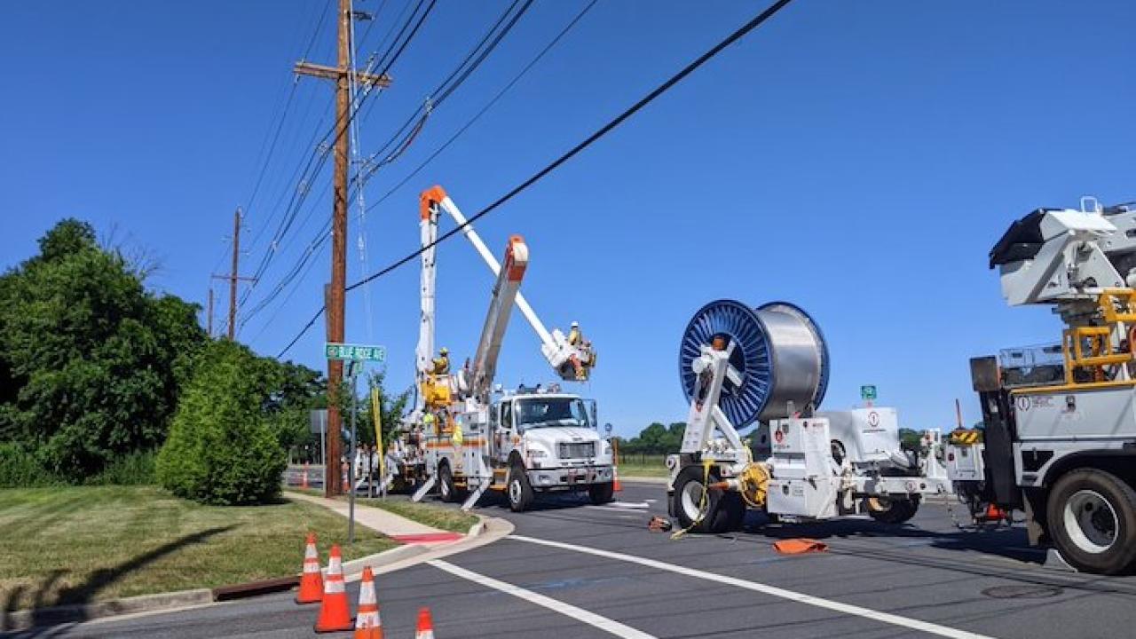 Photo showing PSEG crews updating power lines. Trucks with wiring and a cherry picker are shown.