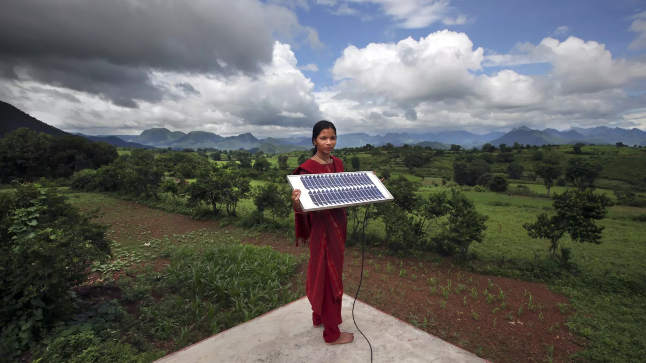 person holding solar panel with beautiful landscape behind