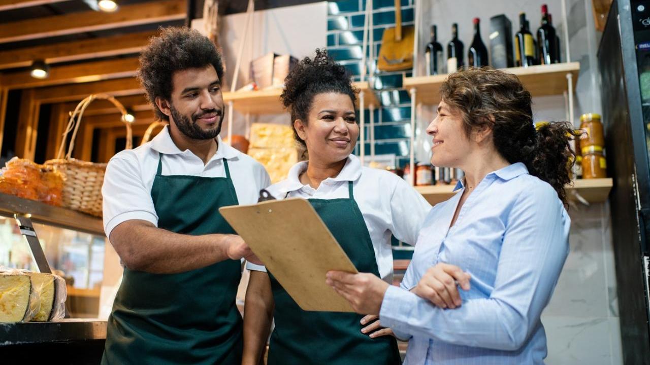 Three retail workers reviewing notes on a clipboard