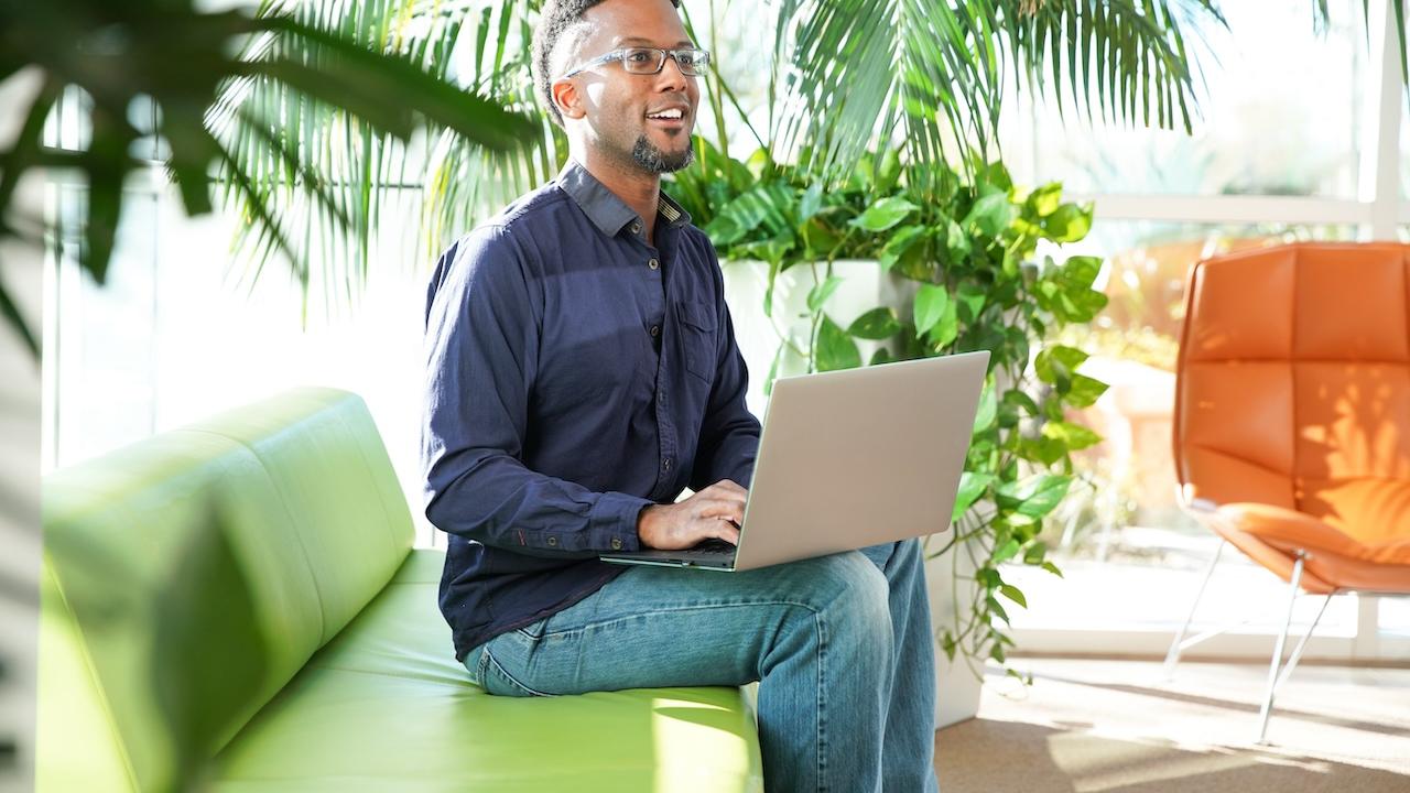 Person seated on a couch with a laptop.