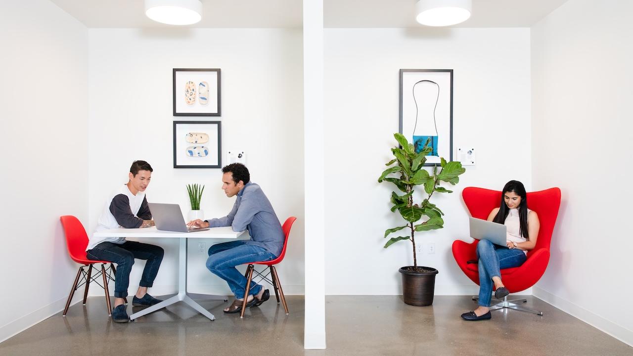 Three people seated and working on laptops.