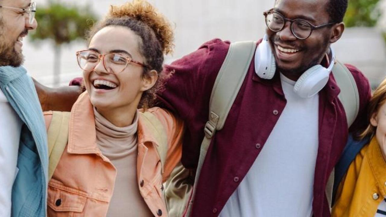 Four people with their arms around each other smiling