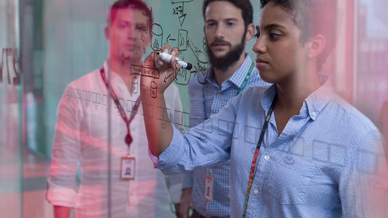 A person writing on the transparent board