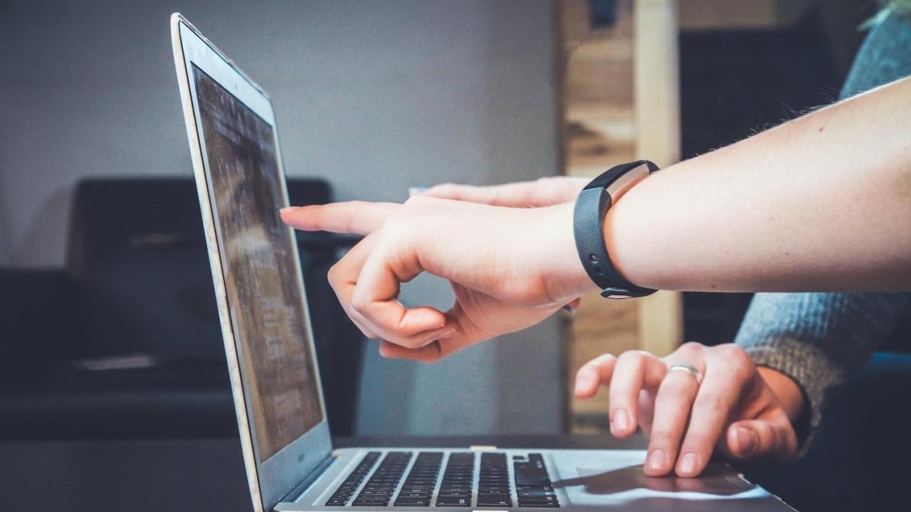 Person touching laptop screen