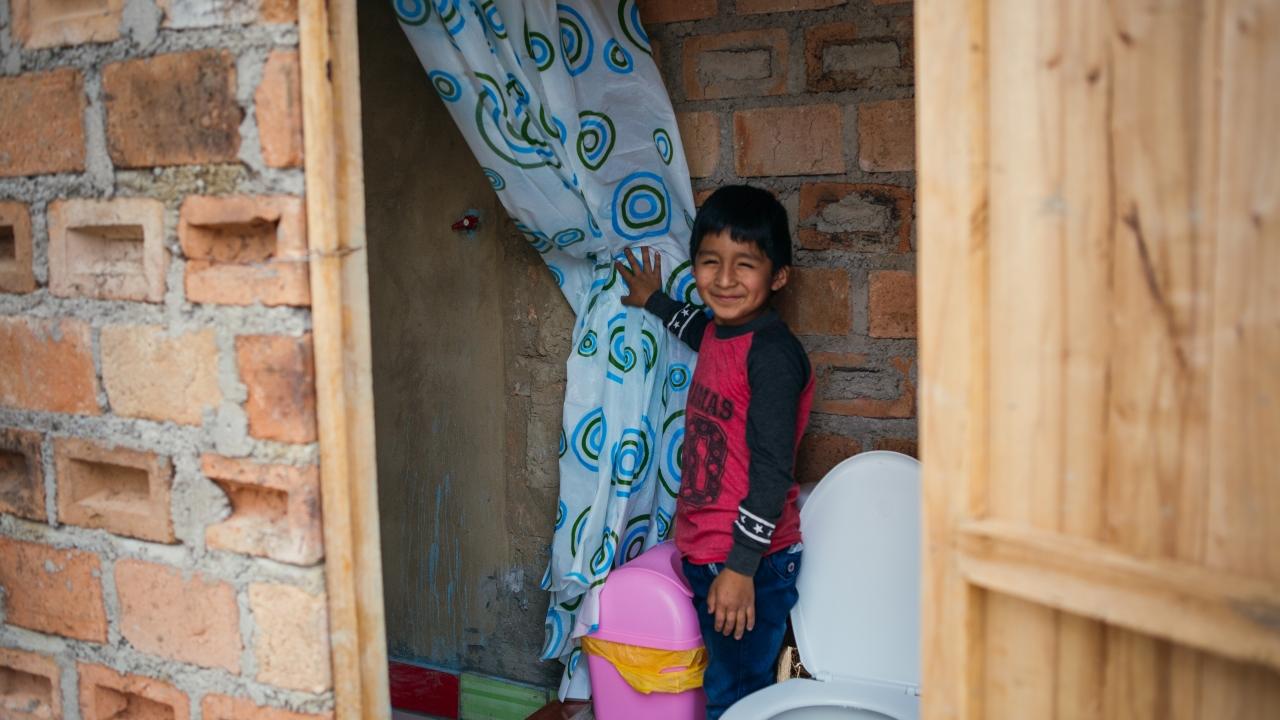 Young boy shows his family's new toilet and shower in Peru. 