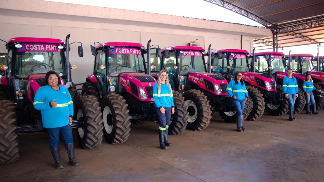Women stood in a line in front of pink tractors 