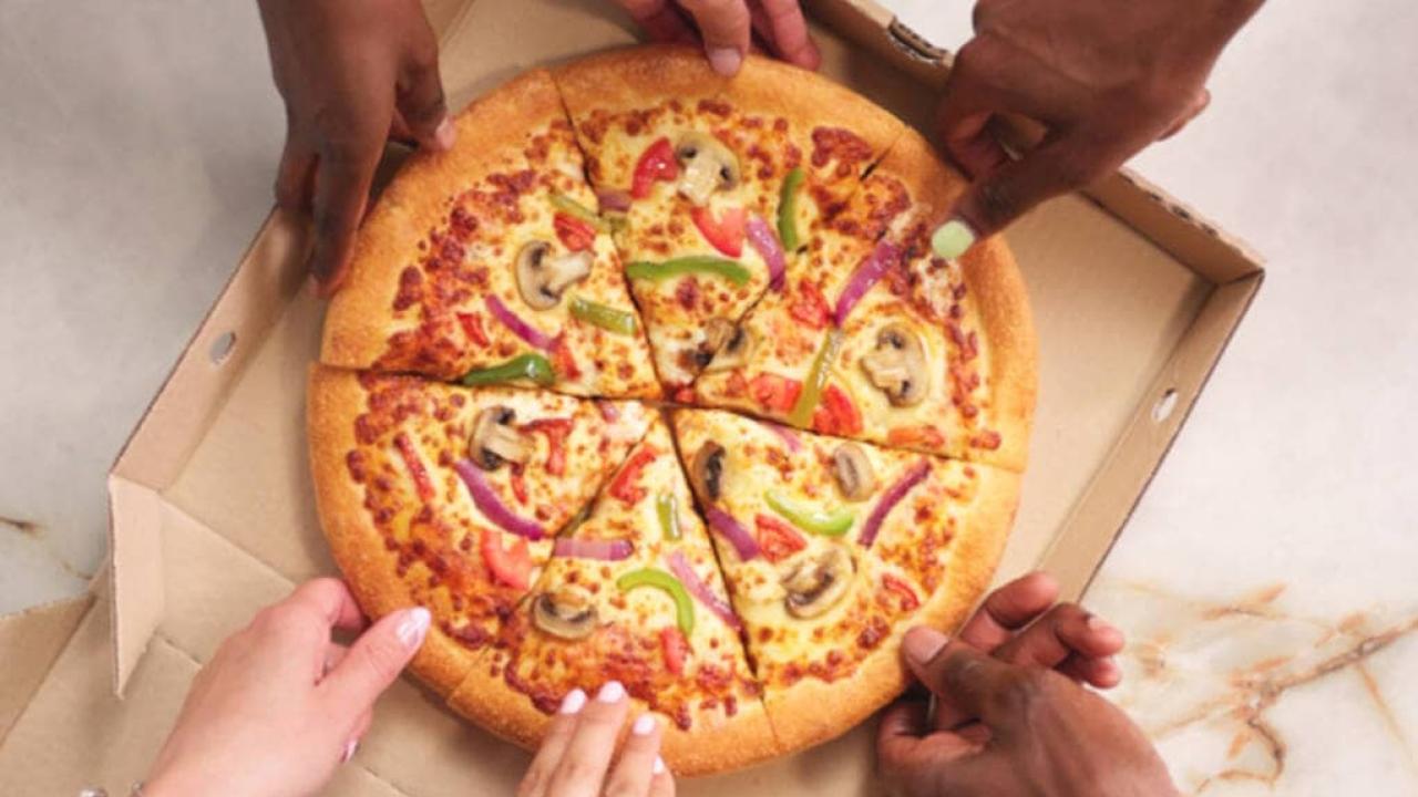People grabbing a slice of pizza from a box