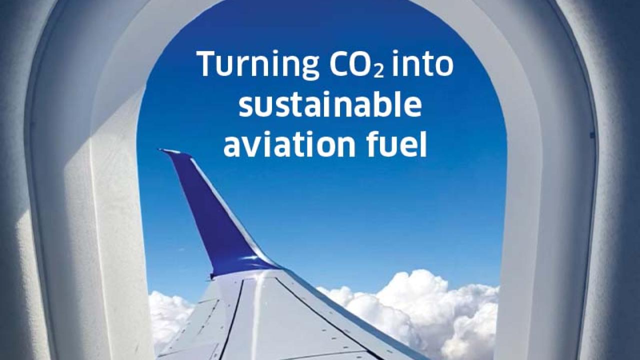 view out a plane window of the wing and "Turning CO2 into sustainable aviation fuel" in the sky