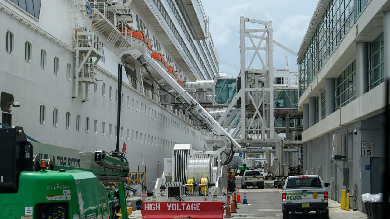 A large boat docked near a narrow roadway and building.