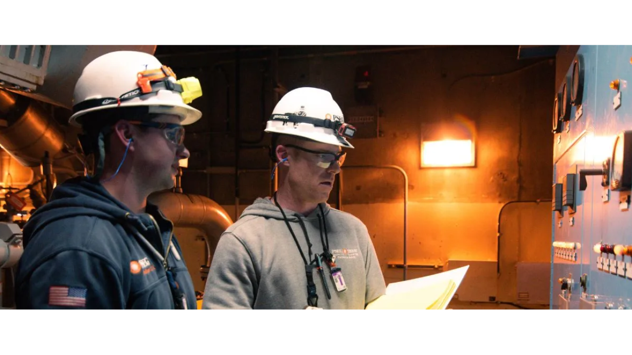 Two people wearing hard hats working in power plant