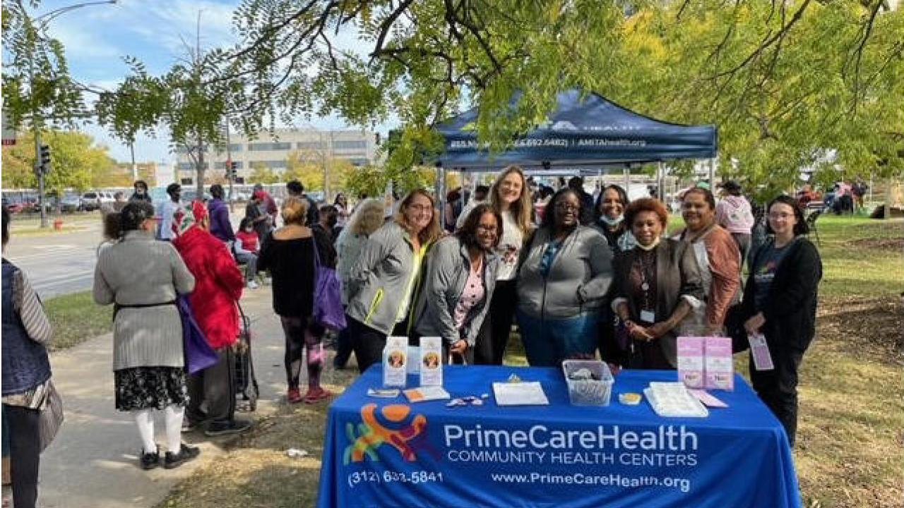 Group standing behind PrimeCare Health table in a park